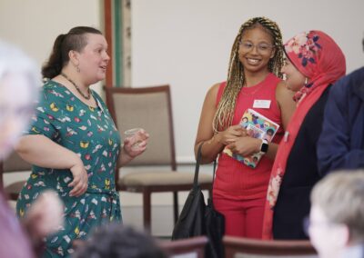 Threee women in bright clothing engaging in an animated conversation.