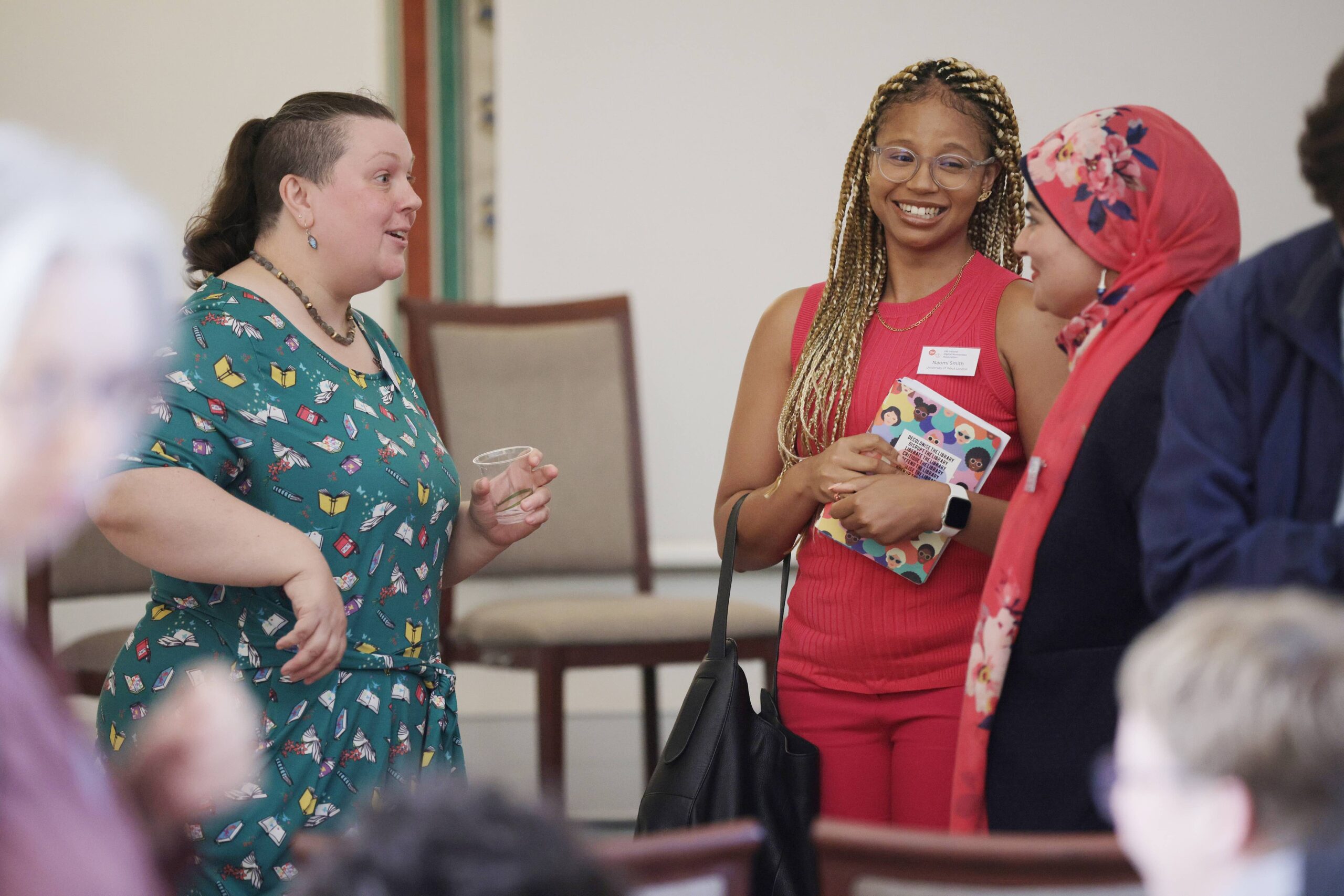 Threee women in bright clothing engaging in an animated conversation.