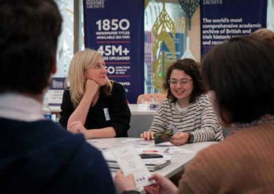 This image shows delegates discussing during the Digital Humanities Climate Coalition workshop. We see the backs of two delegates in the foreground, and in the background we see two delegates smiling and laughing while discussing.
