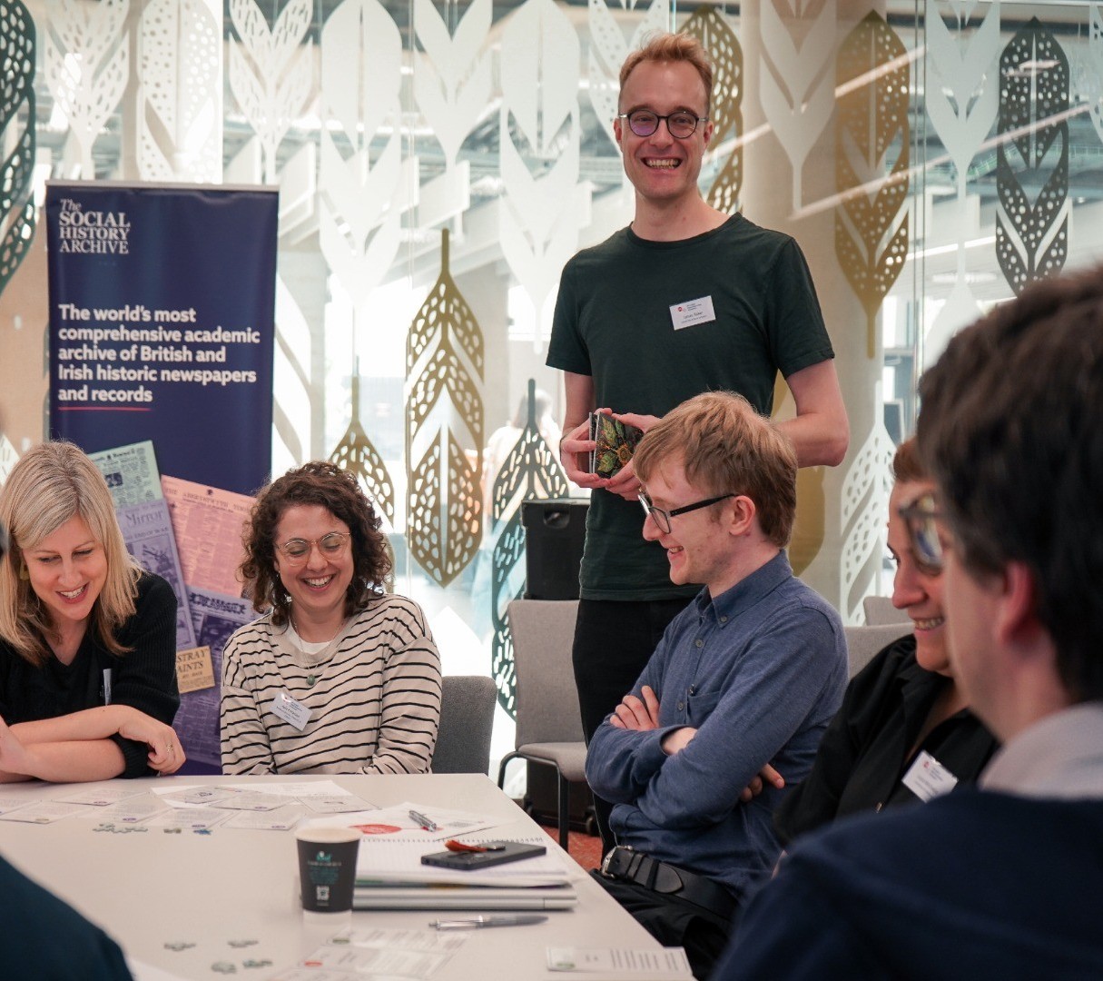 This image shows delegates discussing during the Digital Humanities Climate Coalition workshop. We see the backs of two delegates in the foreground, and in the background we see two delegates smiling and laughing while discussing.