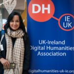 This image shows delegates discussing during the Digital Humanities Climate Coalition workshop. We see the backs of two delegates in the foreground, and in the background we see two delegates smiling and laughing while discussing.